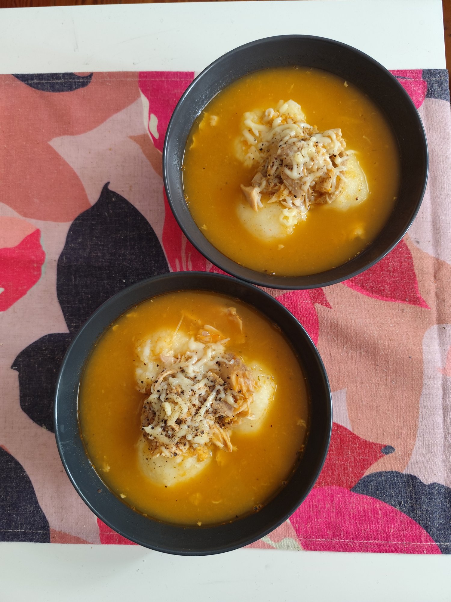 Zwei Schalen Kürbissuppe mit pochierten Eiern, geschmolzenem geriebenem Käse, knusprigen Zwiebeln und schwarzem Pfeffer