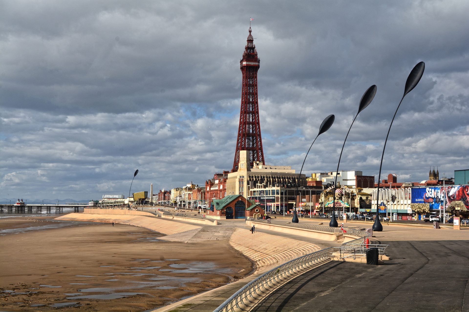 La Blackpool Tower sopra il lungomare e i gradoni della diga, con la spiaggia con la bassa marea