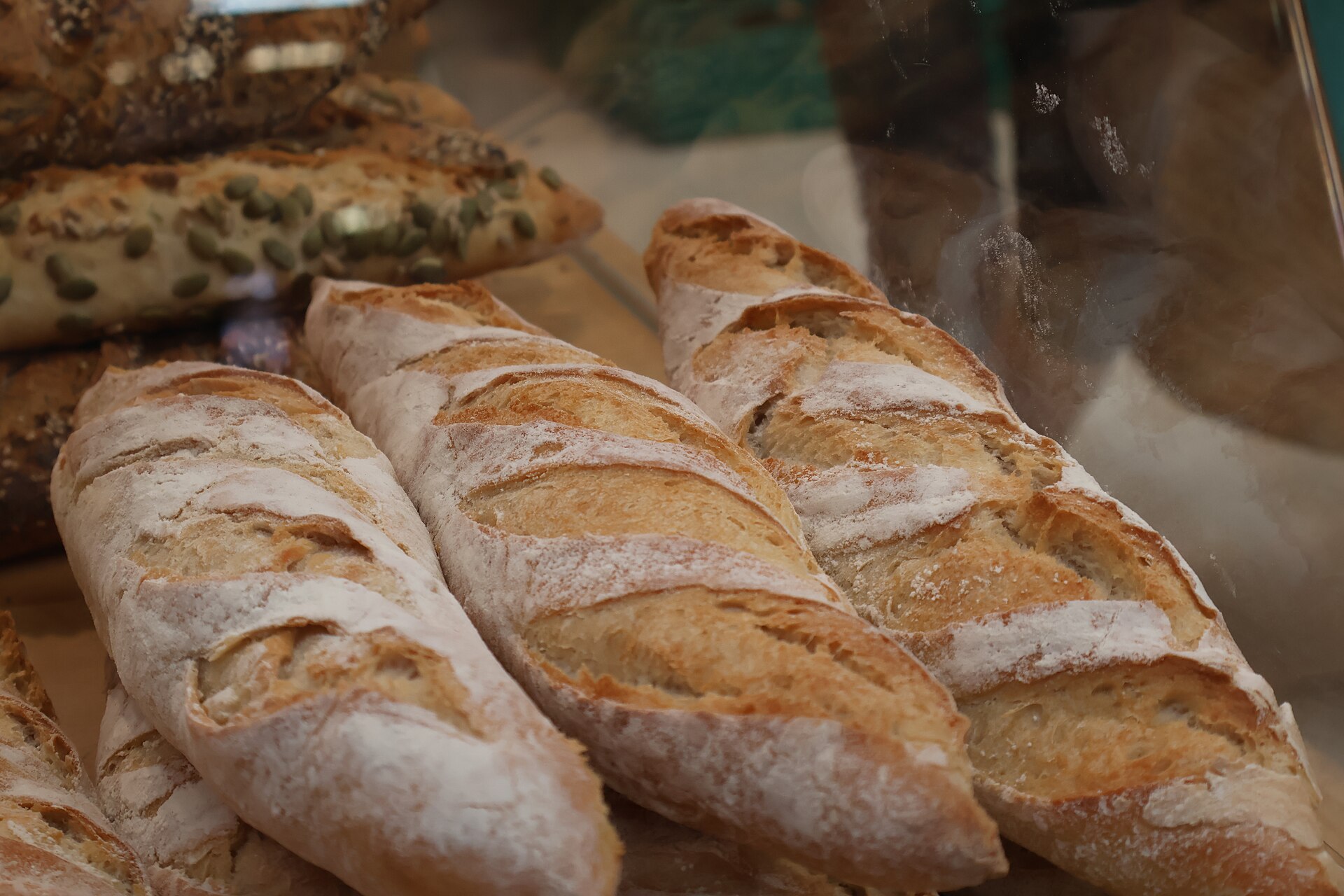Rustic crusty loaves dusted with flour, with seeded bread behind
